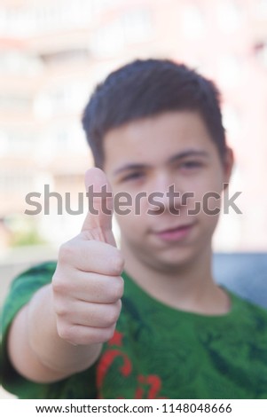 Happy casual teenager showing thumb up and smiling, concept about people, education and lifestyle