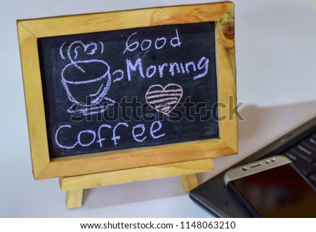 Good Morning Coffee written on a chalkboard on it and smartphone, laptop.