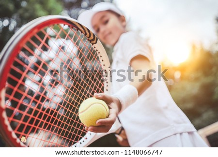 Sporty little girl preparing to serve tennis ball. Close up of beautiful yong girl holding tennis ball and racket. Child tennis player preparing to serve. Royalty-Free Stock Photo #1148066747