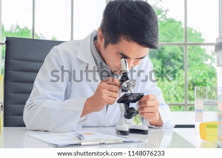 Asian Male doctors or scientist using microscope to study and research on the biology at the Science Laboratory.Concept Science and Medical image.