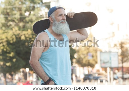 Happy old man. The concept of life satisfaction. Portrait of a positive gray-haired man with a skateboard. Winner concept.