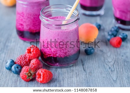 Smoothies of fresh berries and fruits in glass glasses on a gray wooden table. Soft focus.