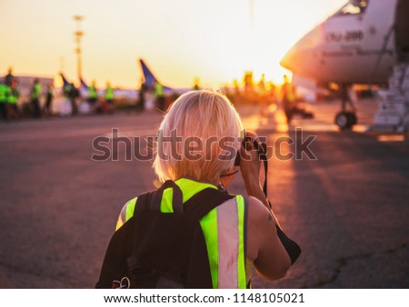 a girl spotter photographs a plane at the evening