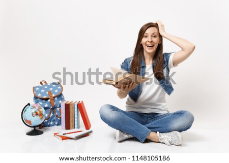 Young amazed laughing woman student in denim clothes hold book keeping hand near head sit near globe, backpack, school books isolated on white background. Education in high school university college