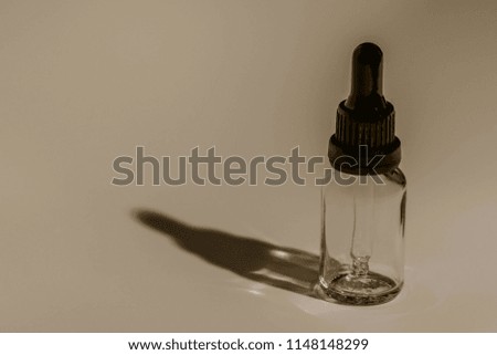 Closeup of single eye dropper bottle with strong dark shadow on white background. 