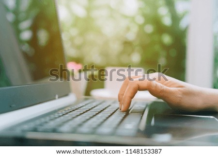 Woman hand using laptop to work study with cafe shop colorful highlight shade to object beautiful background. Business, financial, trade stock maket and social network concept.