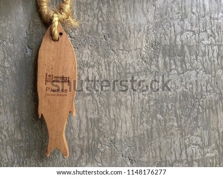 "Please do not disturb" Sing design on the door for hotel room , It is made of wood in the shape of fish. On loft cement wall