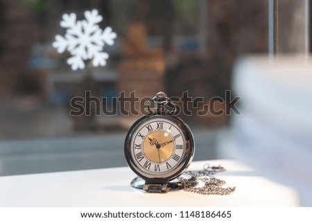 Vintage pocket watch next to window and snow flake, festival concept