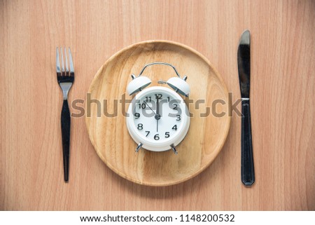 The clock is at 12:00 noon for lunch in a wooden dish.