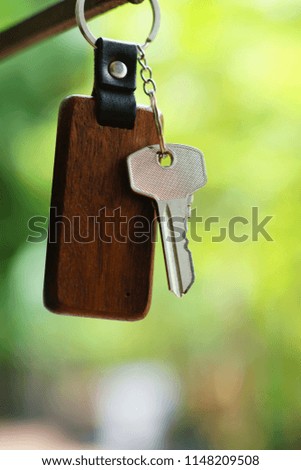House keys with wooden home keyring with blur green garden background, property concept, copy space