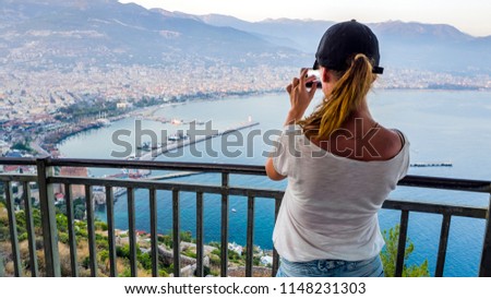 Young Girl - traveler,  taking picture ,  viewing Alanya city and beaches from the viewpoint of the mountain: "Alanya Kalesi"