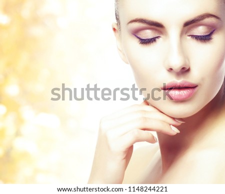 Portrait of young, natural and healthy woman over yellow autumn background.