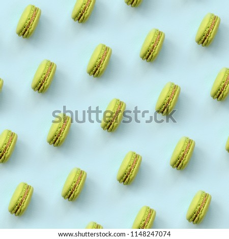 Green dessert cake macaron or macaroon on trendy pastel blue background top view. Flat lay pattern composition