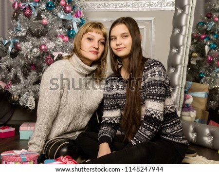 happy mother and teenag daughter near christmas tree at home laugh and hug