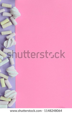 Colorful marshmallow laid out on violet and pink paper background. pastel creative textured framework. minimal