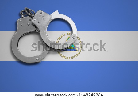 Nicaragua flag  and police handcuffs. The concept of crime and offenses in the country