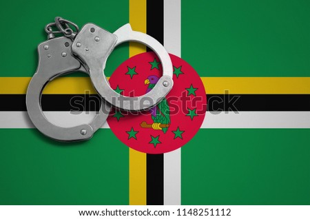 Dominica flag  and police handcuffs. The concept of crime and offenses in the country