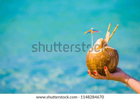 Coconut with an umbrella and a tube on the background of the sea
