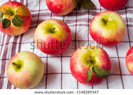 Fresh red apples with green leaves on a napkin. Dark wooden background