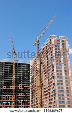 Unfinished high building. Many tower cranes near the house