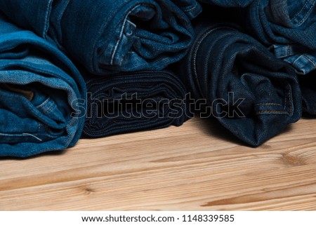 Roll Frayed jeans or blue jeans denim collection on rough wooden table background with copy space, old fashion style concept.