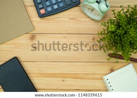Office supplies or office work essential tools items on wooden desk in workplace, pen with notebook and calculator and alarm clock with copy space, top view