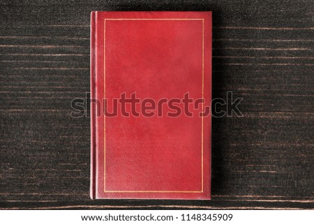 Book with red blank cover on dark wooden background