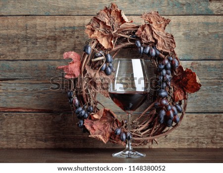 Glass of red wine with grapes and dried vine leaves. Copy space for your text. 