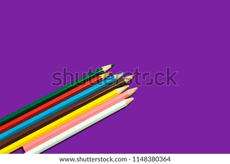 line of colored pencils lying diagonally on a purple background. concept of office and educational chancery. free space for advertising text