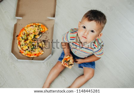 charming boy sitting on the floor eating pizza top view