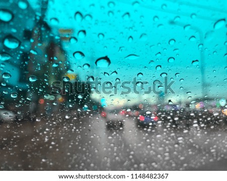 Rain Drops on the windshield, traffic in the city on a rainy day at evening, car windshield view, colorful bokeh, dark and blurred background.