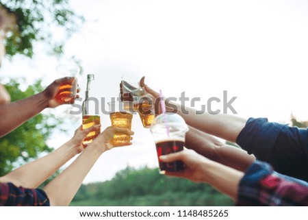 Bottles of beer in people's hands on blue sky background at forest
