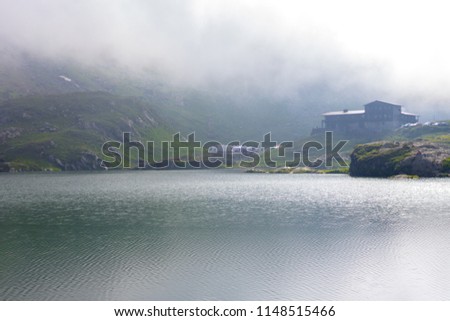 House in the fog on the shore of a mountain lake. 