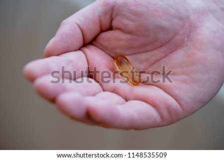 Close up a man hand holding fish oil capsule,Take Vitamin Omega-3 fish oil one a day, A food supplements for elderly people, Healthy life concept