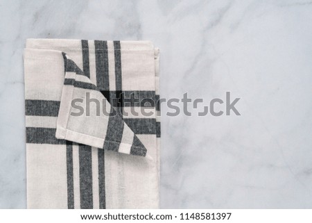 New kitchen towels with simple black pattern folded on marble counter.
