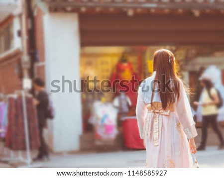 travel and tourist korea concept from beautiful woman in korea traditional cloth (hanbok) relax, take picture in vintage town with soft focus dress rental shop background