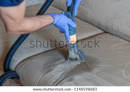Closeup of upholstered Sofa chemical cleaning with professionally extraction method. Man is holding nozzle. Royalty-Free Stock Photo #1148598683
