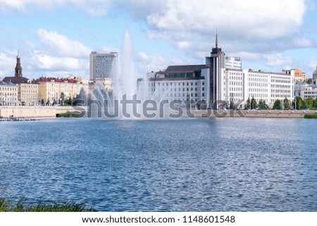 View of buildings from the other side of the river. Fountain. Splashing water. Cityscape. Office building.