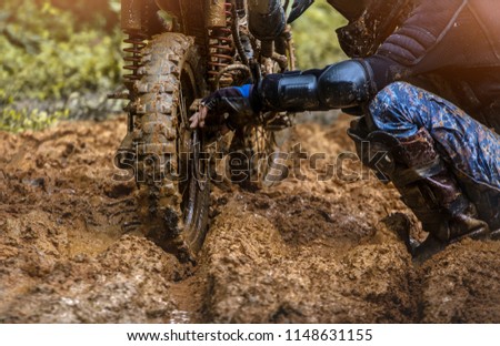 Rider man fixing motocross on mud road.