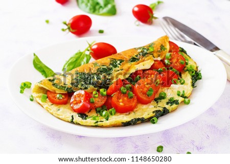 Omelette with tomatoes, spinach and green onion on white plate.  Frittata - italian omelet. Royalty-Free Stock Photo #1148650280