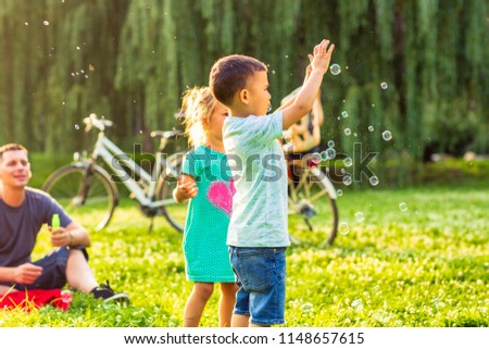 Happy Family-Cheerful cute children chase bubbles in nature
