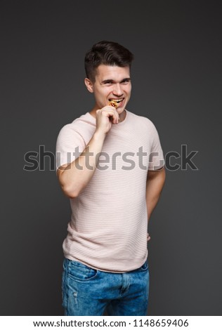 young guy bites a coin bitcoin with his teeth, checking for authenticity, isolated on a gray background. Royalty-Free Stock Photo #1148659406