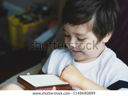 Happy little boy having fun playing game on mobile phone,Preschool kid sititng on sofa with smiling face watching cartoon on smart phone,Child using cell phone while relaxing at home