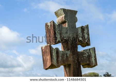 Jesuit christian cross in stone with sky in background