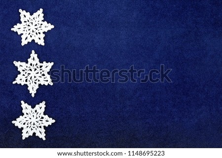White crocheted snowflakes on blue velvet background