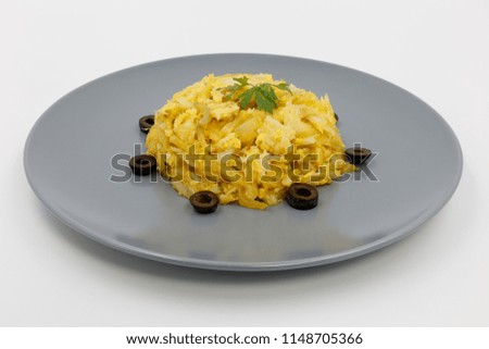 codfish with potato chips, scrambled eggs and black olives