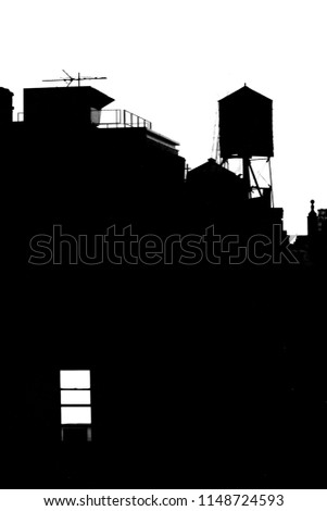 Black and white New York City building with water tower and window with light on 