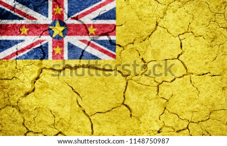 Niue flag on dry earth ground texture background
