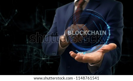 Businessman shows concept hologram Blockchain on his hand. Man in business suit with future technology screen and modern cosmic background