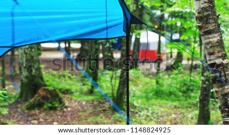 Camping site in the rainy summer day. Tourist tents installed in the forest. Survival camping equipment in the harsh climatic conditions. Forest background with rain soaked tents. 